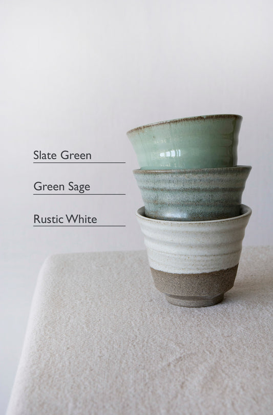Handmade pottery espresso mugs with raw clay base arranged in a calming minimalist composition.