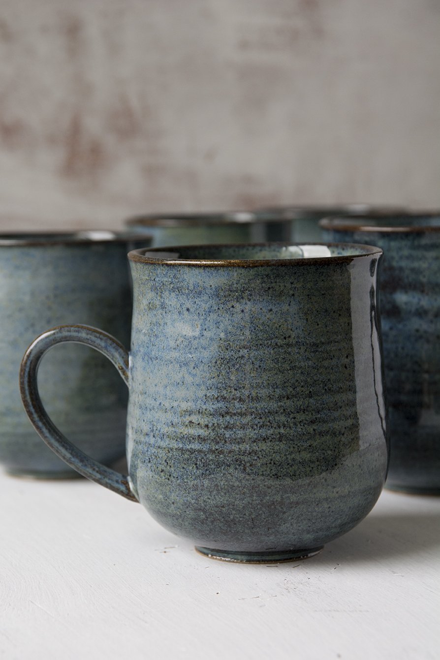 Hand-thrown blue pottery mug with a rustic finish, ideal for farmhouse-inspired kitchen decor