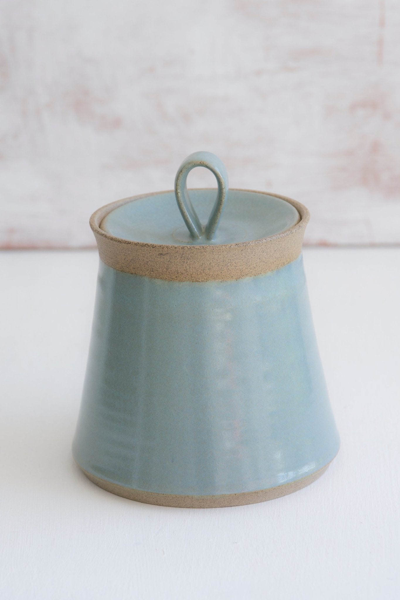 Minimalist light blue ceramic container with subtle ridges, storing cotton swabs in a clean farmhouse setting